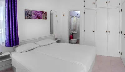 a white bedroom with a white bed and a purple curtain at Two bedroom apartment with garden view in Luz in Luz