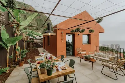 a patio with a wooden table and chairs at Mango House in Arco da Calheta