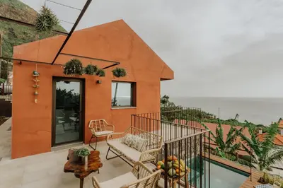 a house on a balcony with the ocean in the background at Mango House in Arco da Calheta