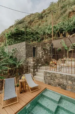 a patio with two chairs and a swimming pool at Mango House in Arco da Calheta