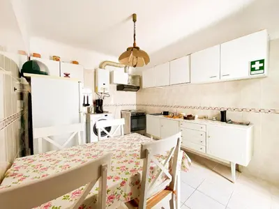 a kitchen with white cabinets and a dining table at Simple Beach Lovers' Retreat in Espiche #1888 in Espiche