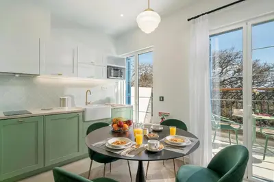 a kitchen with green cabinets and a table with fruit on it at Madeira Gems Apartments in Funchal