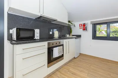 a kitchen with white cabinets and a microwave at Ilha Natura in Santana
