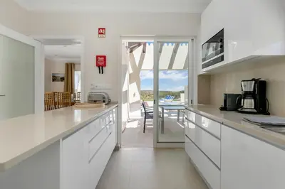 a kitchen with white countertops and a dining room at Sea View Villa in Sagres