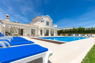 a villa with a swimming pool and blue lounge chairs at Sea View Villa in Sagres