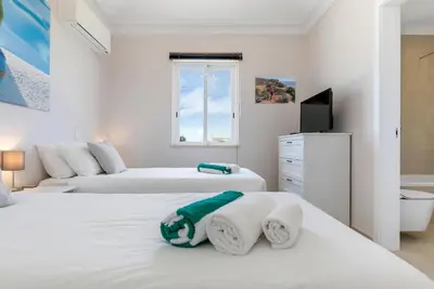 two beds in a white room with a tv at Sea View Villa in Sagres