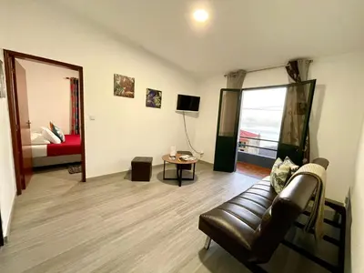 a living room with a leather couch and a window at Sunset Star with Sea View in Calheta