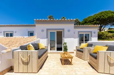 a patio with couches and a table in front of a house at Beach Villa - oceanfront villa Martinhal in Sagres
