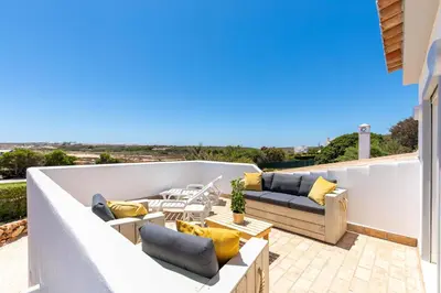 a patio with couches and chairs on a balcony at Beach Villa - oceanfront villa Martinhal in Sagres