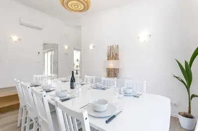a white dining room with a white table and white chairs at Beach Villa - oceanfront villa Martinhal in Sagres