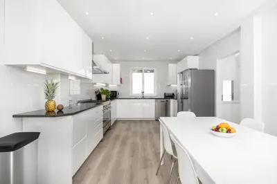 a white kitchen with a white table and chairs at Beach Villa - oceanfront villa Martinhal in Sagres