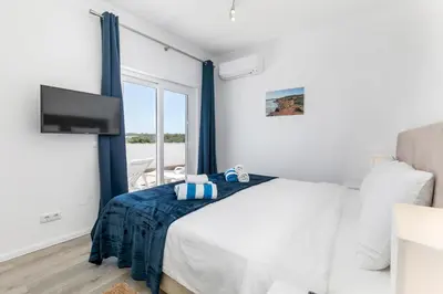 a bedroom with a bed and a tv and a window at Beach Villa - oceanfront villa Martinhal in Sagres