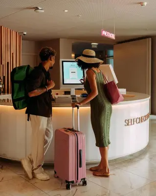 a man and a woman standing at a counter with luggage at NEXT - by Savoy Signature in Funchal