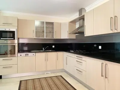 a kitchen with white cabinets and black counter tops at Charming Calheta Plaza Penthouse in Calheta