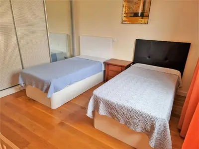 a bedroom with two beds and a wooden floor at Charming Calheta Plaza Penthouse in Calheta