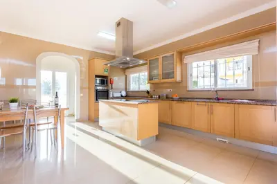 a large kitchen with wooden cabinets and a table at CoolHouses Algarve Luz, 5 bed villa & pool, Casa N in Luz