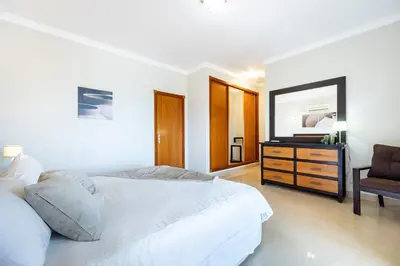 a white bedroom with a bed and a chair at CoolHouses Algarve Luz, 5 bed villa & pool, Casa N in Luz