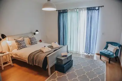 a bedroom with a bed and a blue chair at Quinta do Brasil in Arco da Calheta