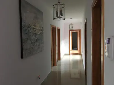 a hallway with white walls and a painting and a chandelier at Quinta do Brasil in Arco da Calheta