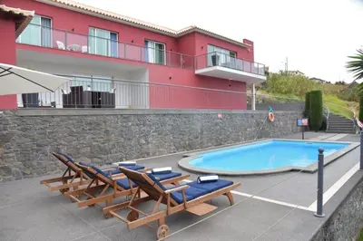 a resort with a swimming pool and chairs and a building at Quinta do Brasil in Arco da Calheta