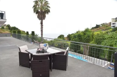 a table and chairs on a balcony with a palm tree at Quinta do Brasil in Arco da Calheta