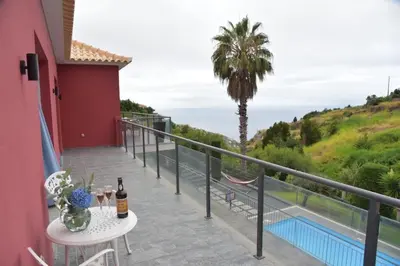 a balcony with a table and a palm tree at Quinta do Brasil in Arco da Calheta