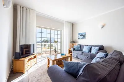 a living room with a couch and a tv at CoolHouses Algarve Luz, 1 bed penthouse flat w/ sea views. Fiji 11 in Luz
