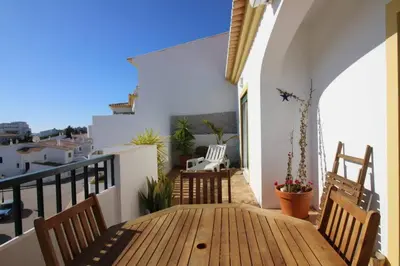 a wooden table and chairs on a balcony at Bright and central apartment - Praia da Luz in Luz