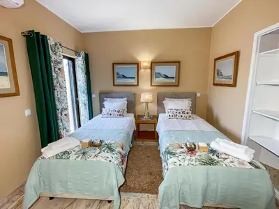 two twin beds in a room with two windows at Casa Canavial in Lagos