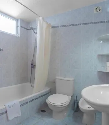 a white bathroom with a toilet and a sink at Sunny Seaside 1 bedroom apartment in Praia da Luz in Luz