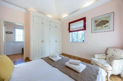 a bedroom with a large white bed and a chair at Casa Gribouille in Sagres