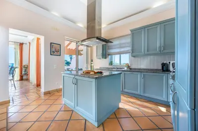 a kitchen with blue cabinets and a tile floor at Casa Gribouille in Sagres