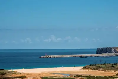 a beach with a pier in the middle of the ocean at Casa Gribouille in Sagres