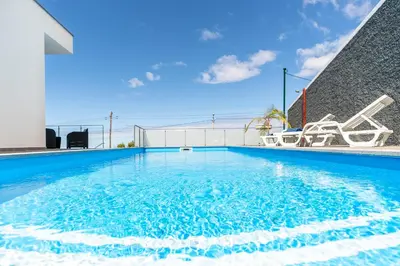 a swimming pool with blue water in a building at CASA GEORGINA in Calheta