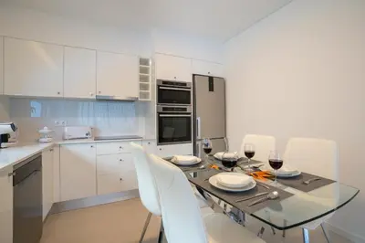 a kitchen with a glass table and white cabinets at CASA GEORGINA in Calheta