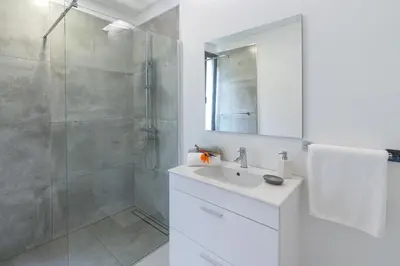 a white bathroom with a shower and a sink at CASA GEORGINA in Calheta