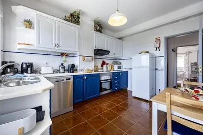 a kitchen with blue and white cabinets and a table at CoolHouses Algarve Luz, 2 Bed top floor flat, amazing sea view, central. Delicia do Sol in Luz