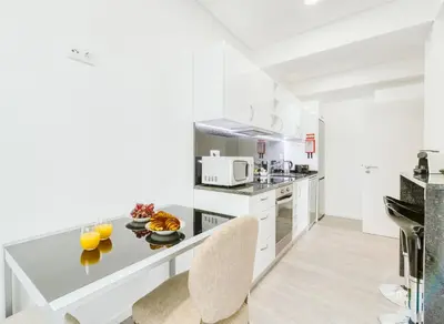 a kitchen with white cabinets and a counter with chairs at Madeira Xhic Apartment by Amazing Madeira in Funchal