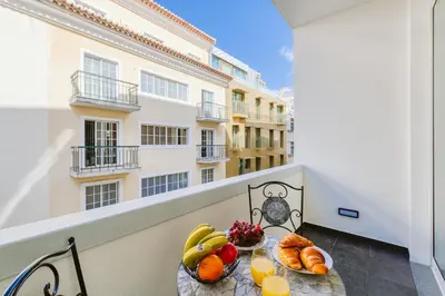 a table with fruit on a balcony with a building at Madeira Xhic Apartment by Amazing Madeira in Funchal