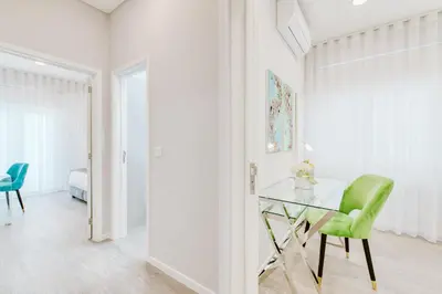 a white room with a glass table and a green chair at Madeira Xhic Apartment by Amazing Madeira in Funchal