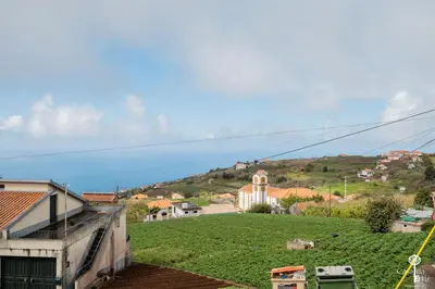 a view of a green hill with a church on it at Casa da Edite in Ponta do Sol