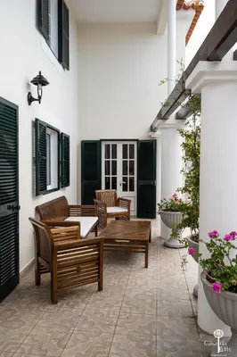 a patio with wooden chairs and a table and some flowers at Casa da Edite in Ponta do Sol
