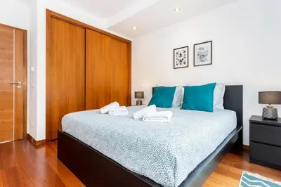 a bedroom with a large bed with blue pillows at Baia da Luz- ground floor apartment in Luz