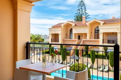 a balcony with a table and chairs and a building at Baia da Luz - Poolview Loft Aparment in Luz