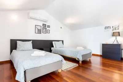 two beds in a room with wooden floors and white walls at Baia da Luz - Poolview Loft Aparment in Luz