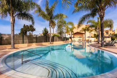 a swimming pool with palm trees in a resort at Baia da Luz - Poolview Loft Aparment in Luz
