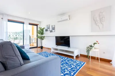 a living room with a couch and a tv at Baia da Luz - Poolview Loft Aparment in Luz