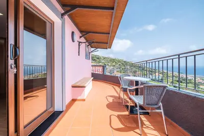 a balcony with a table and chairs and the ocean at Casa do Miradouro -Fantástico Estúdio in Santa Cruz