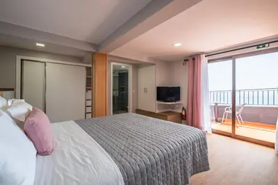 a bedroom with a bed and a view of a balcony at Casa do Miradouro -Fantástico Estúdio in Santa Cruz