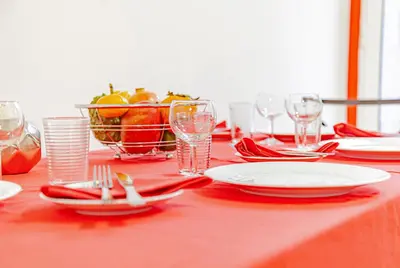 a red table with plates and glasses and a bowl of fruit at Harmony Apartment in Funchal